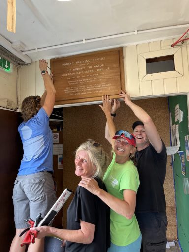 4 people taking down a wooden plaque at HHO